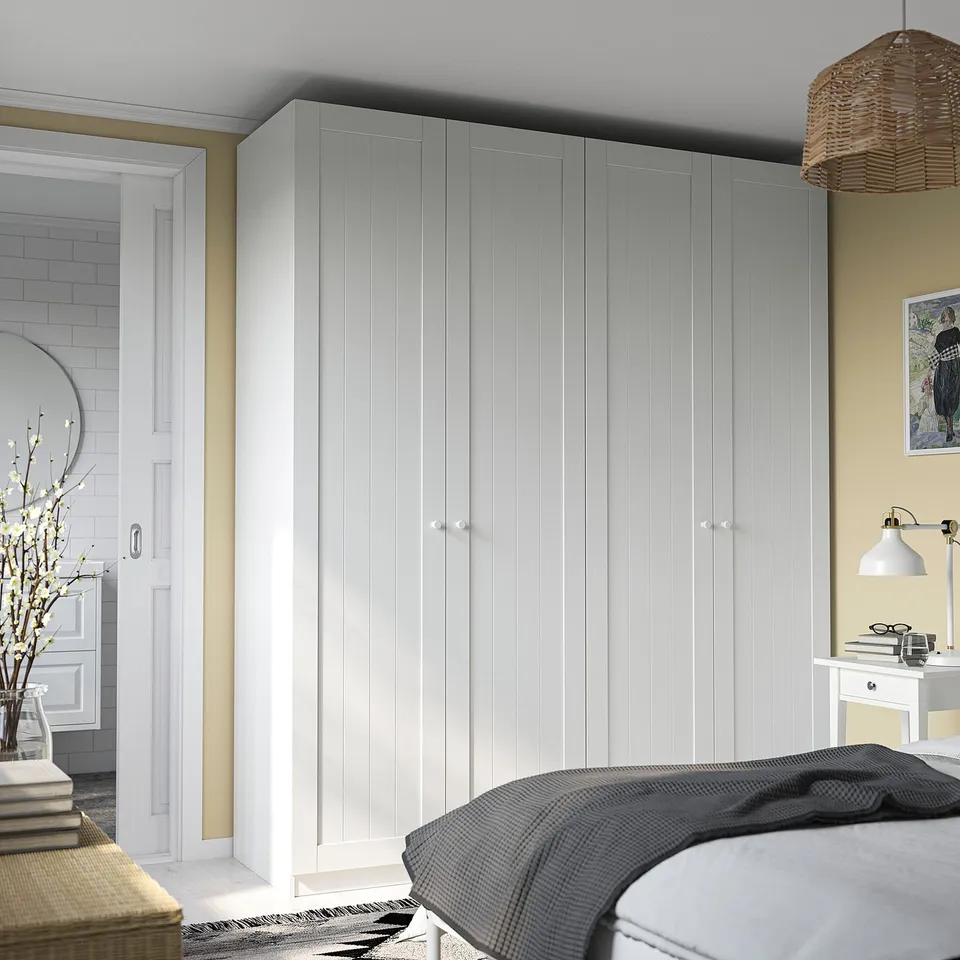 Minimalist bedroom with large white PAX wardrobe, desk, and bathroom view.