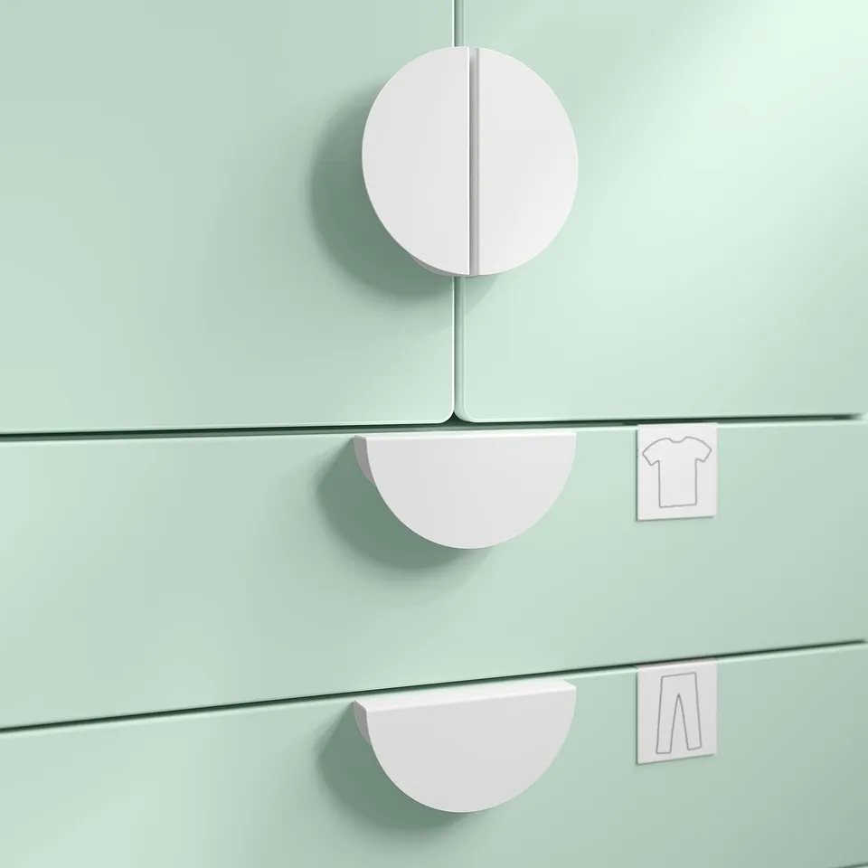 Three pastel pink, circular storage handles attached to light green surfaces.