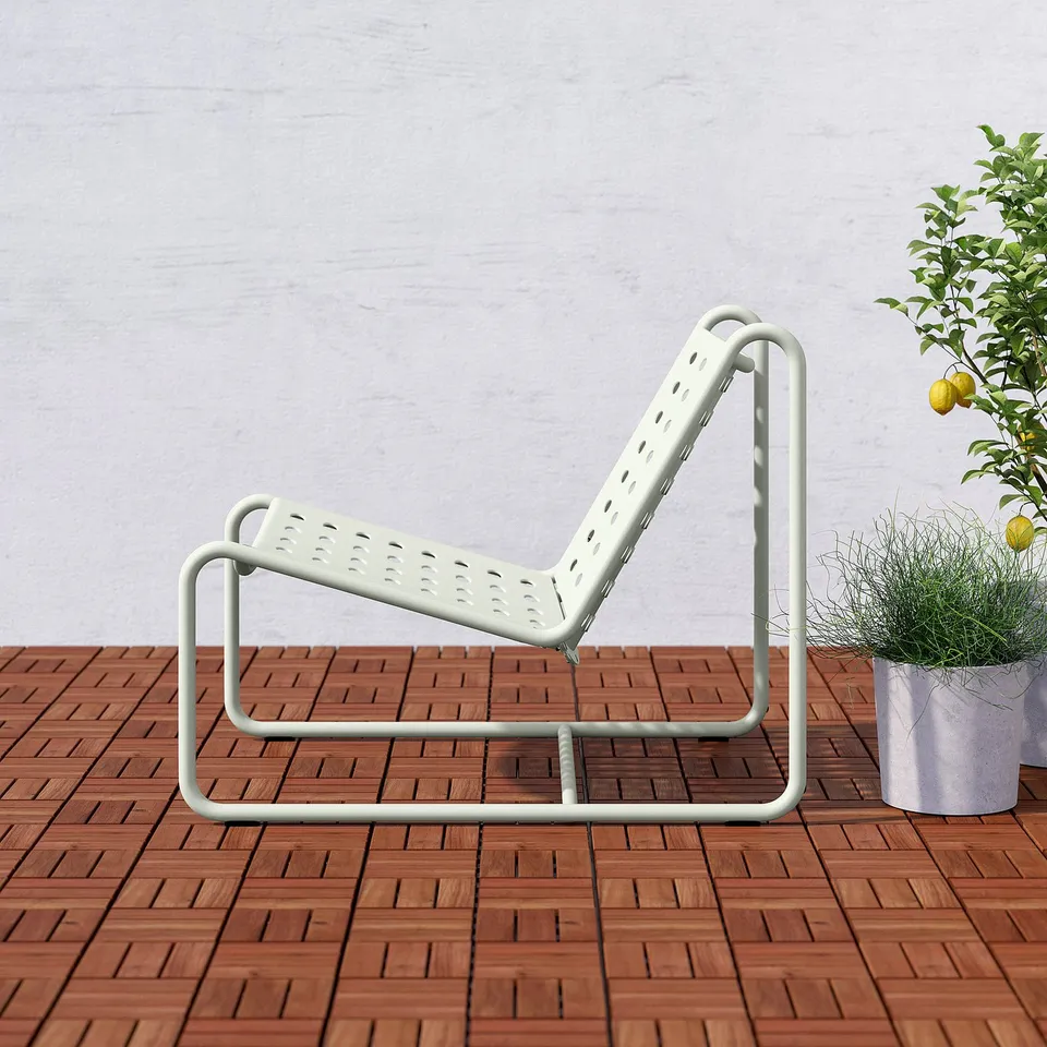 White metal patio chair with perforated seat, three legs, leans back for relaxation.