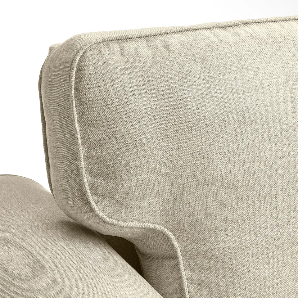 Sofa with smooth, plush beige fabric. Curved back and armrests, stitched lines for style.