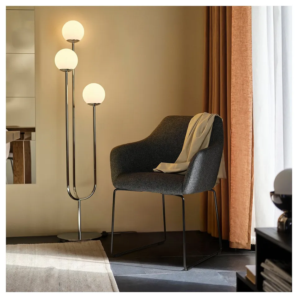 Modern living room: grey TOSSBERG chair, bushes fabric, curved back & armrests, tall floor lamp.