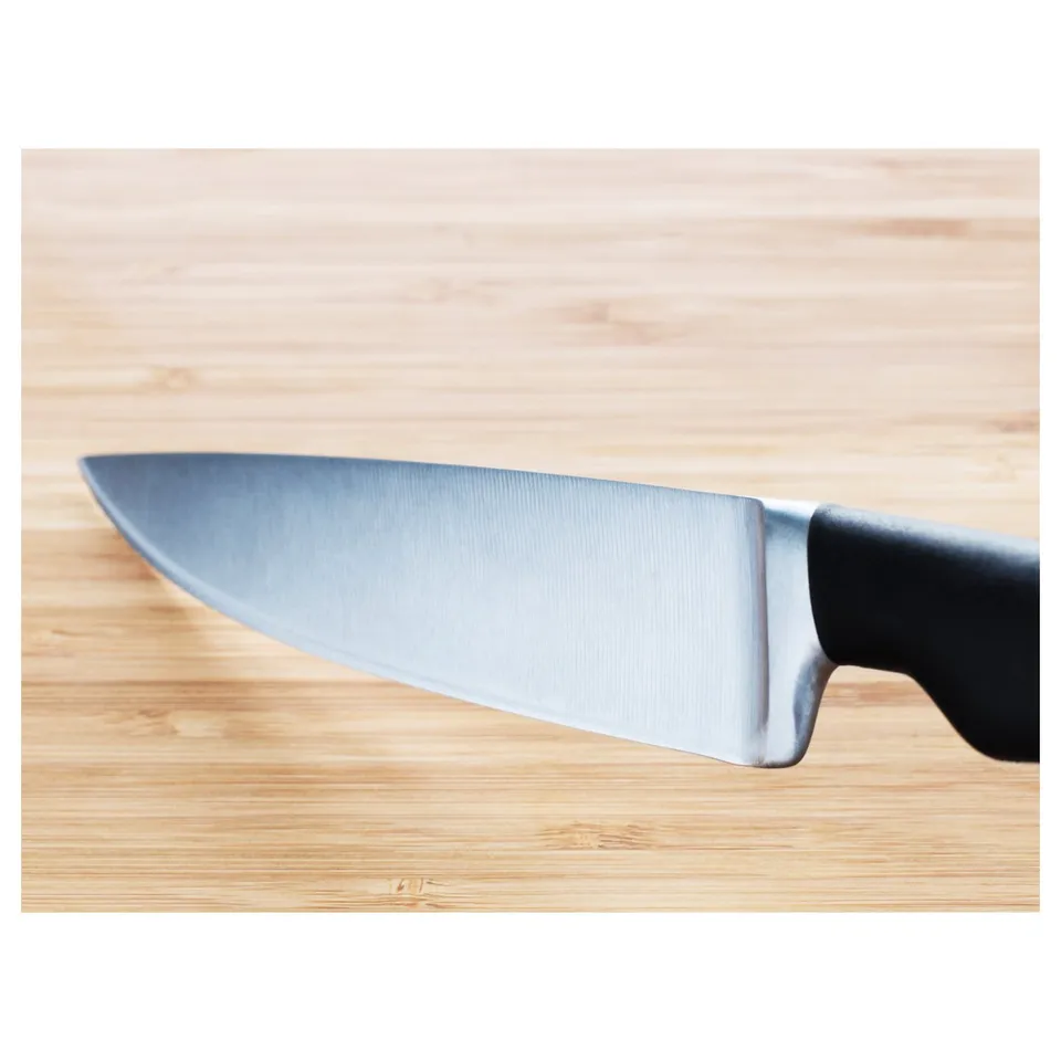 A sharp, stainless steel knife with black handle on a wooden surface, showing high quality and design.