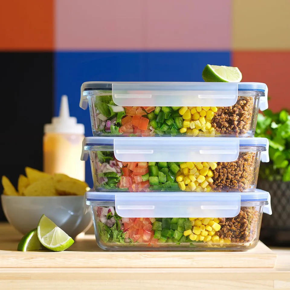 Stacked glass meal prep containers with lids, filled with colourful salad, corn, and ground meat, ready for storage or transport.