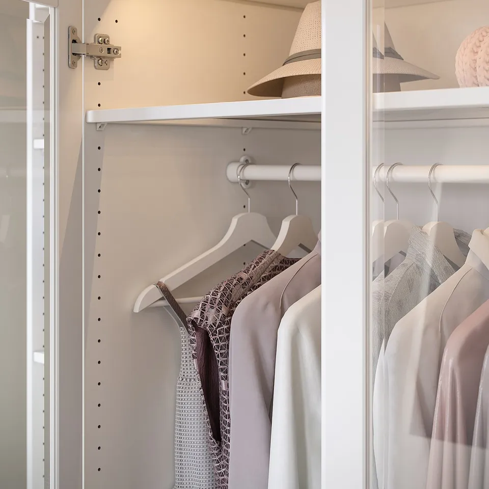 White wardrobe with hanging clothes and hat, organised and sleek.