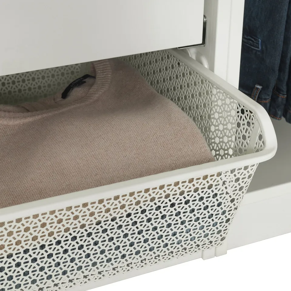 White wardrobe with patterned metal basket storing folded beige clothes.