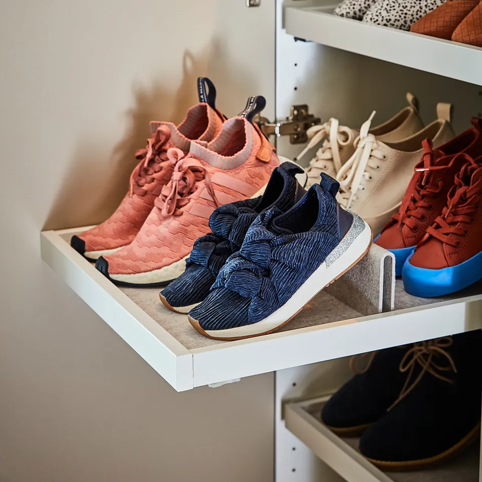 A closet shelf holding white drawers with colourful trainers in hues of pink and blue, featuring a felt insert.