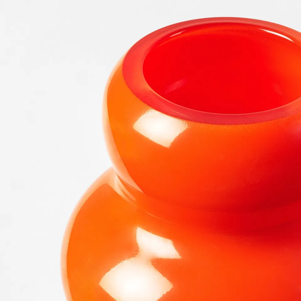 Bright orange glass vase with smooth, glossy finish and curved design, reflecting light beautifully, showcasing high-quality craftsmanship.