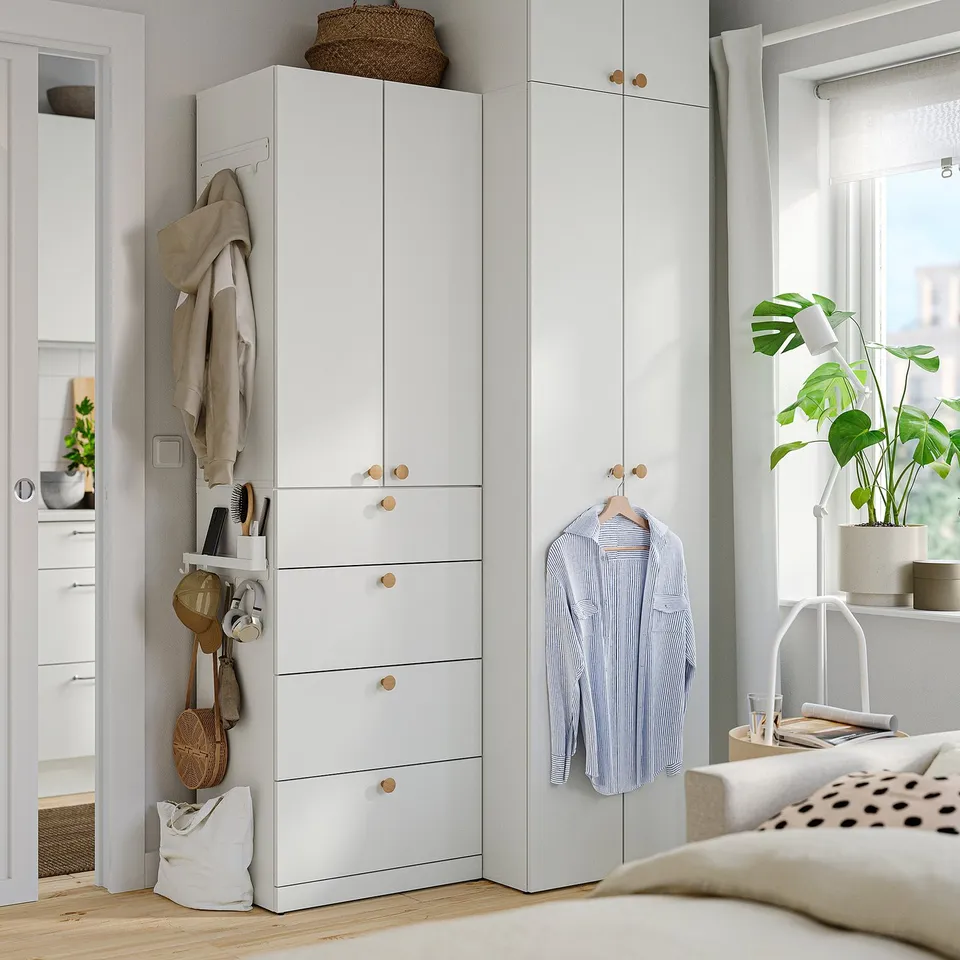 Bedroom with ALTARLIDEN rack, jackets, minimalist decor. Bed, pillow, plant.