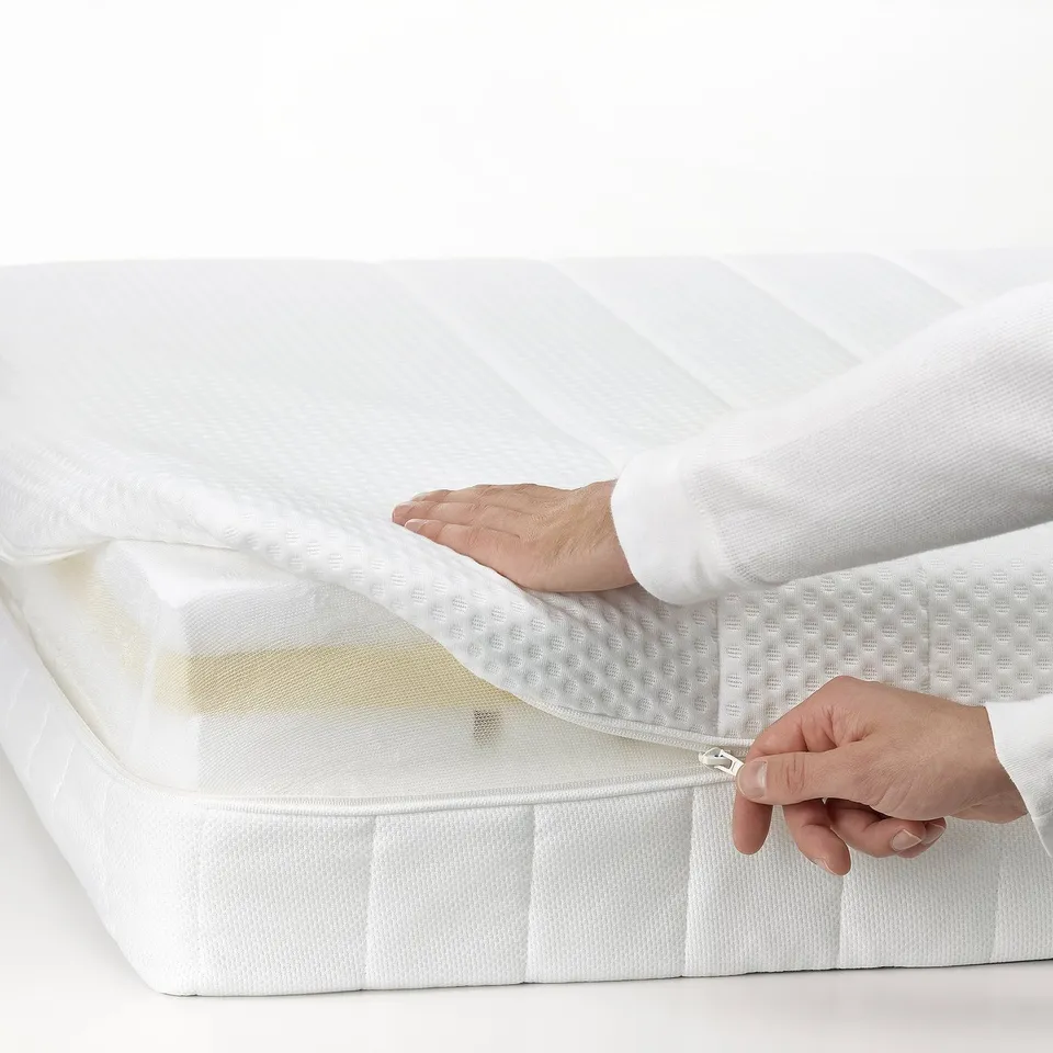 Person zips up white mattress cover, showcasing ease of washing feature.