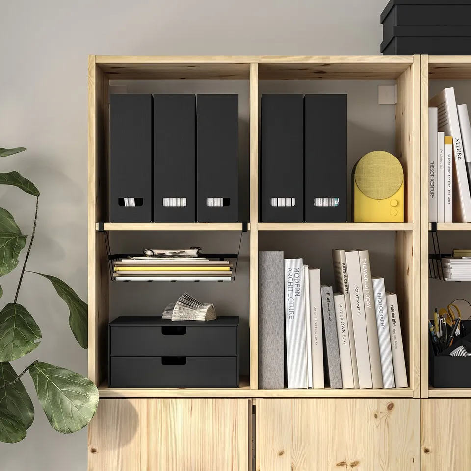 Modern wooden shelf with black folders, books, yellow speaker, and plant. Organised storage with clips and adjustable shelves.