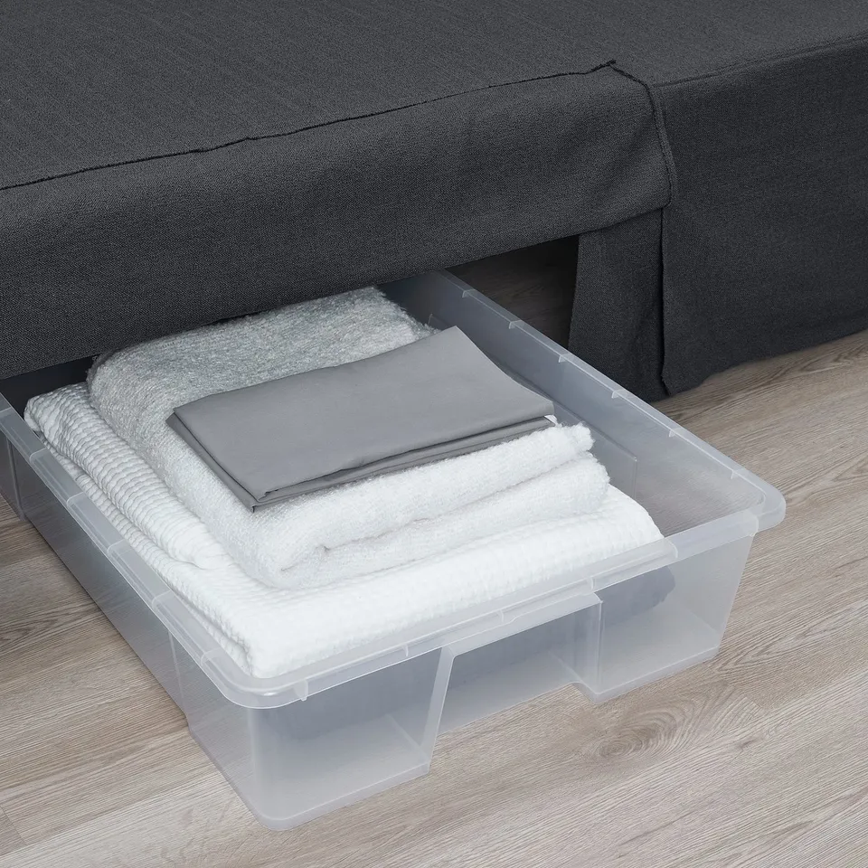 Clear bin under sofa stores folded linens, maximising space.