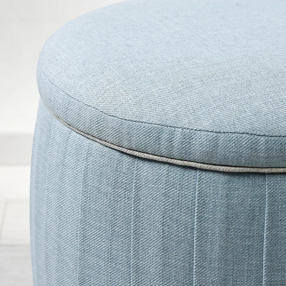 Circular light blue cushioned stool with neat stitching detail, showcasing quality upholstery.