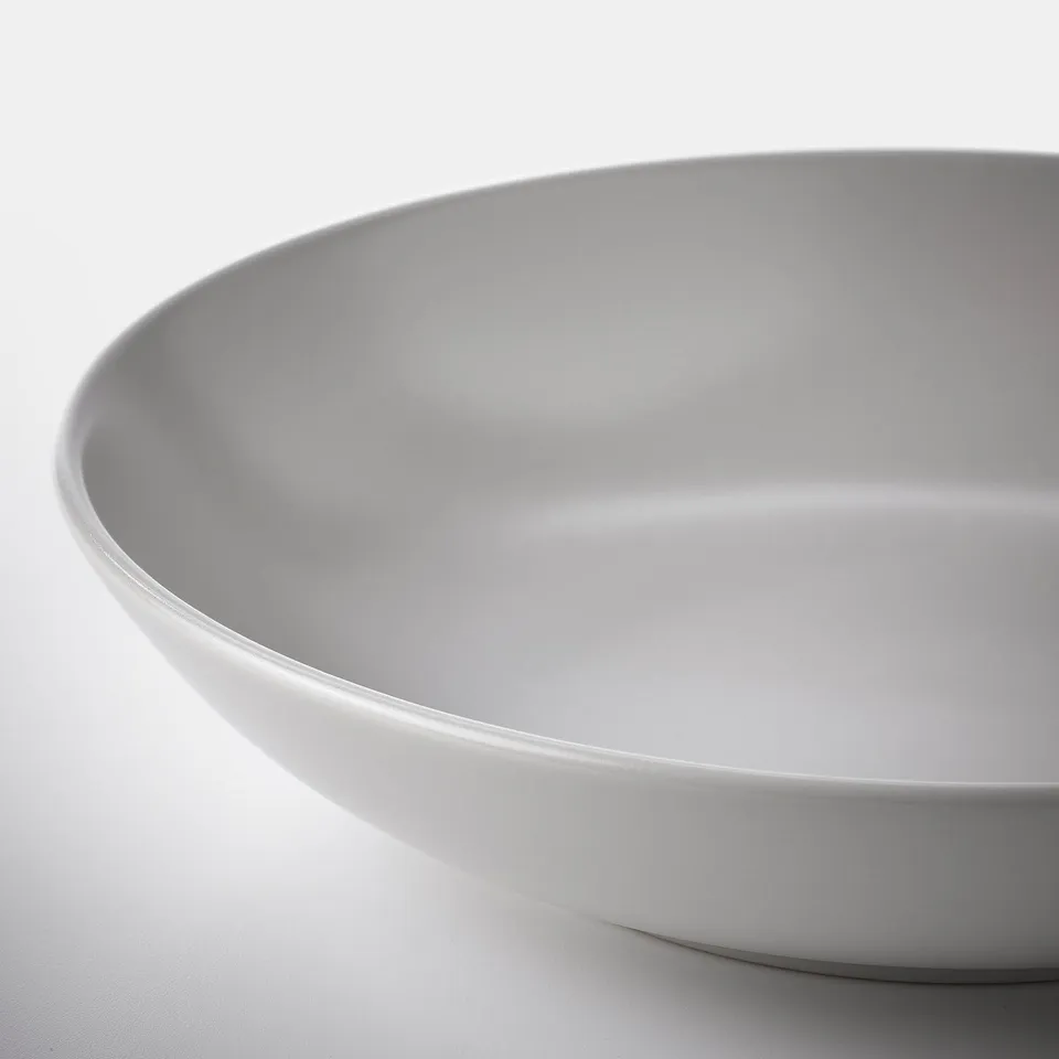 Close-up of a smooth, high-quality white bowl on a white surface.