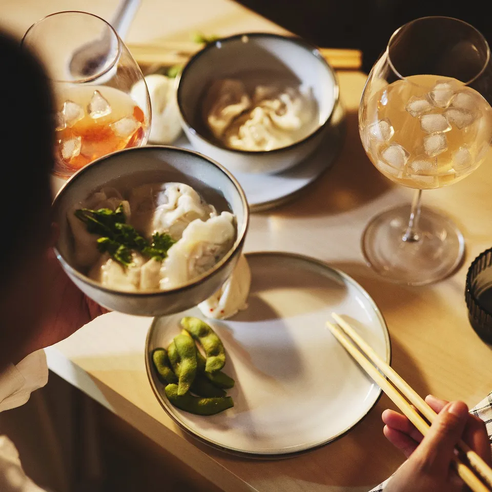 Dining table set with bowls, chopsticks, and wine glasses with ice.