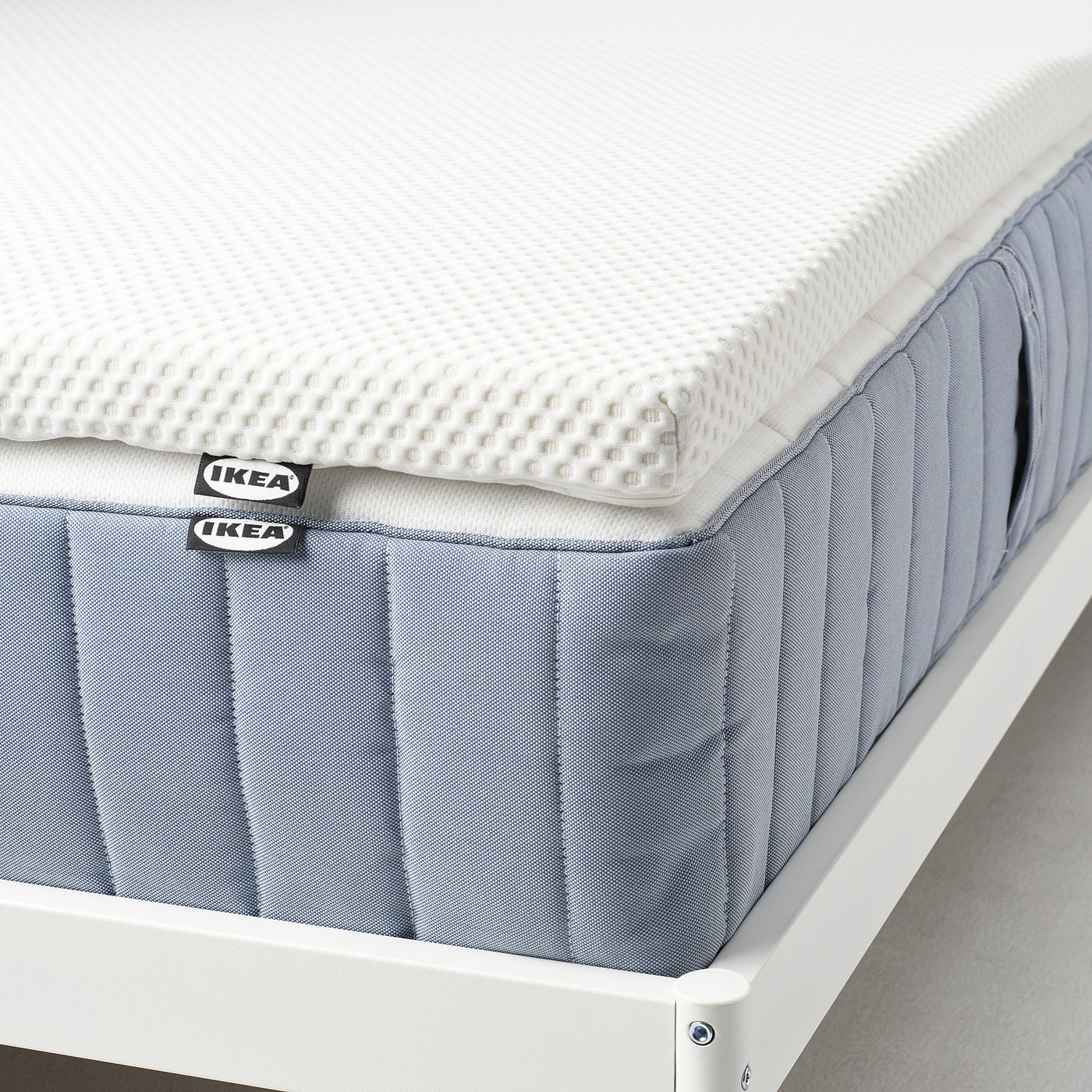 IKEA NORDBERGET memory foam mattress pad on bed, white cover, soft and pressure-relieving.