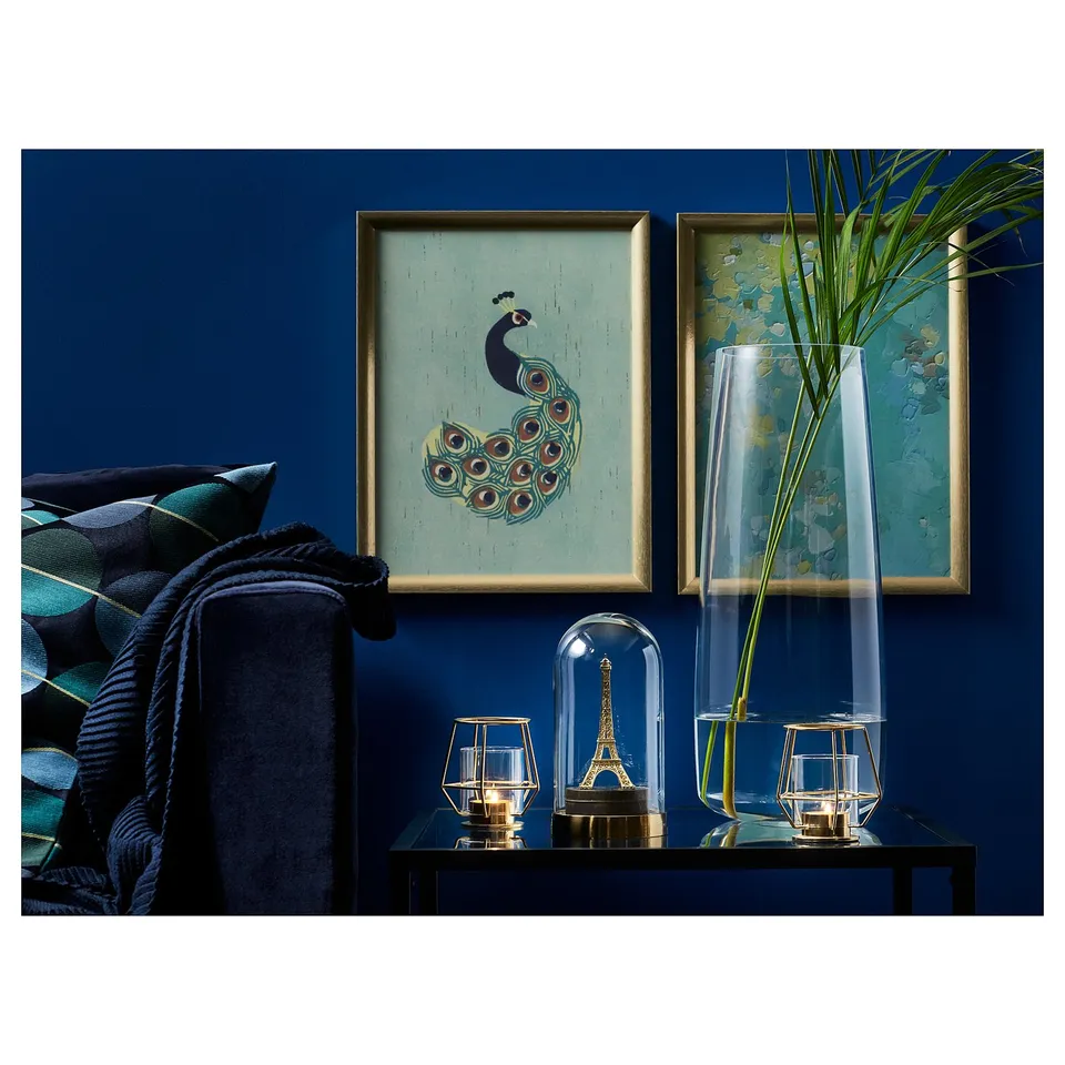 Blue living room with peacock art, plant, black couch, golden decor.