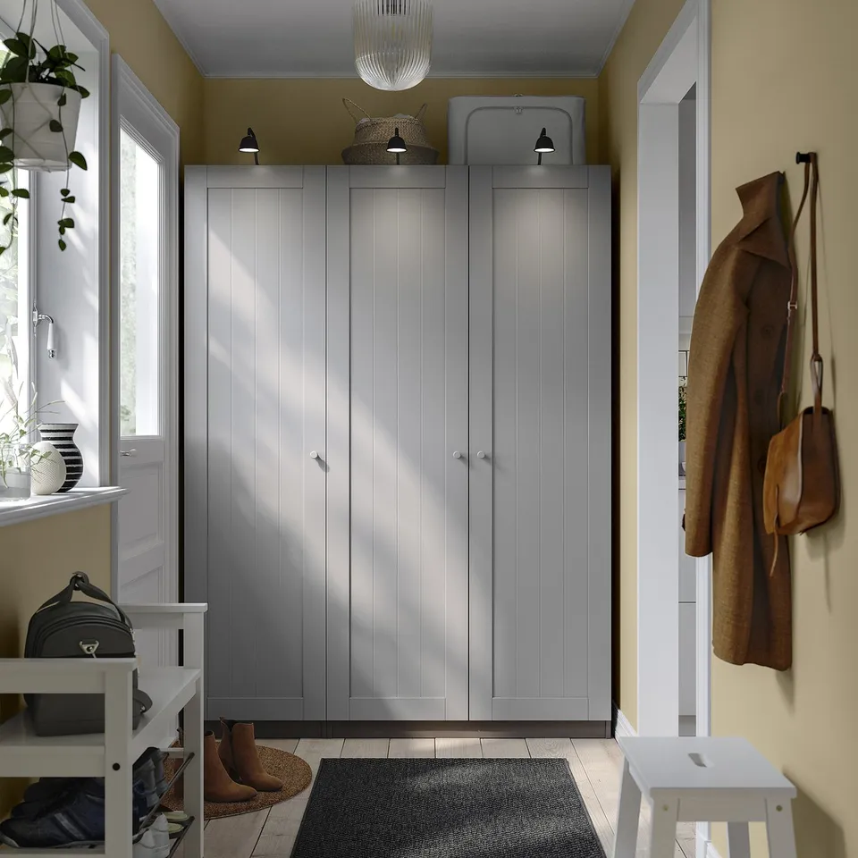 Modern grey PAX closet in entryway with a brown coat, black bag, and white furniture.