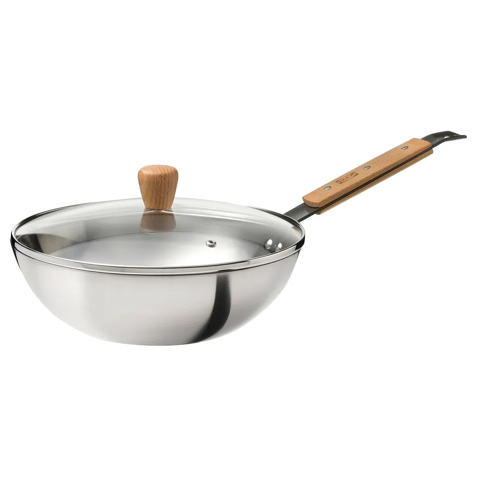 A VARDAGEN wok with a wooden handle and glass lid, designed for even heat distribution and quick cooking.