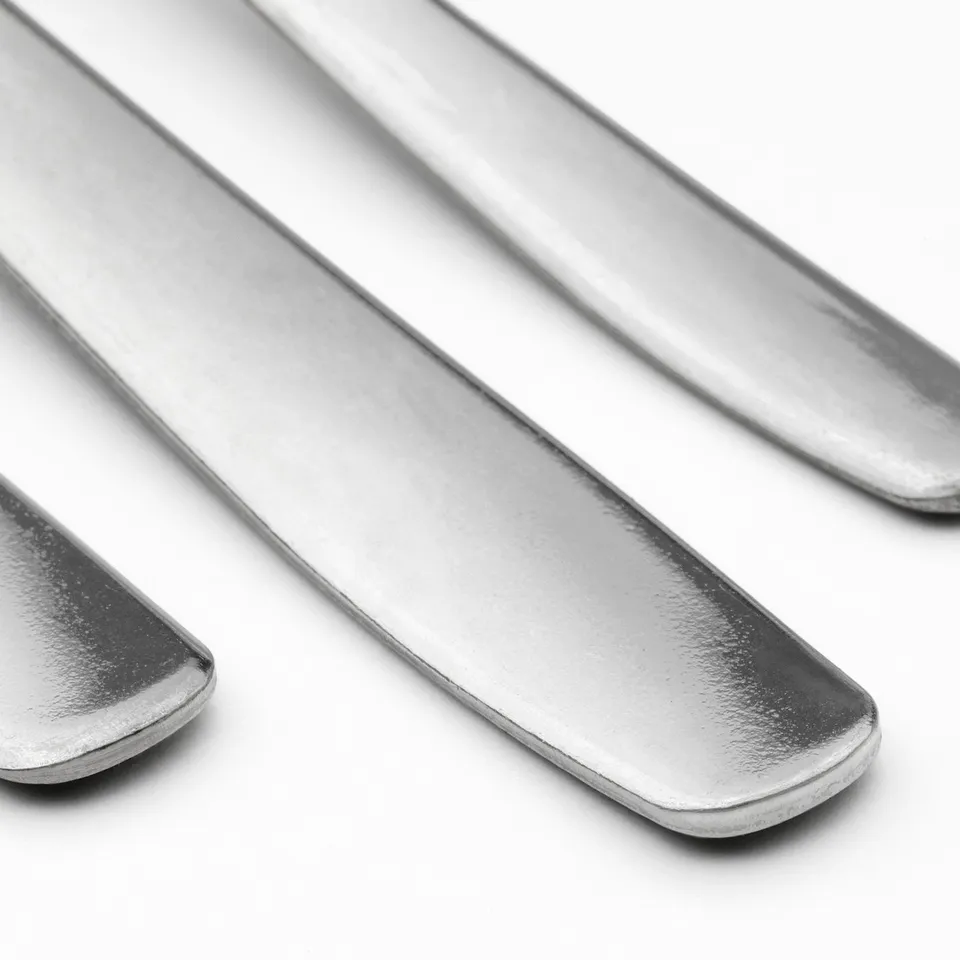 Three polished metal utensils, likely stainless steel, arranged neatly in a row, showcasing their smooth, reflective surfaces and clean design.