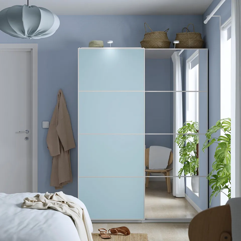 Modern bedroom with blue wardrobe, bed, & plant.