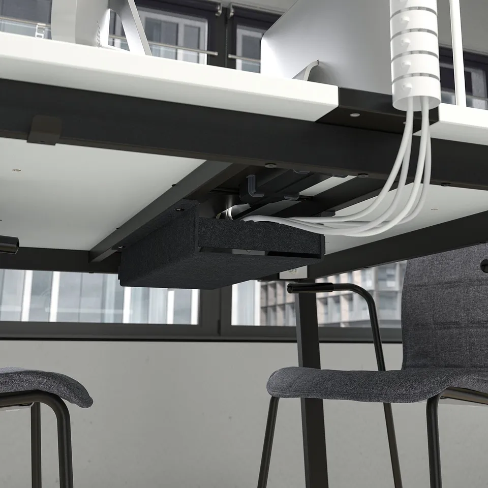 Underside of modern office table with visible cable management and support legs.