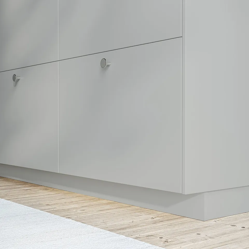 White kitchen cabinets with sleek, round handles attached to a light wooden floor. The cabinets appear smooth and modern, providing storage space.