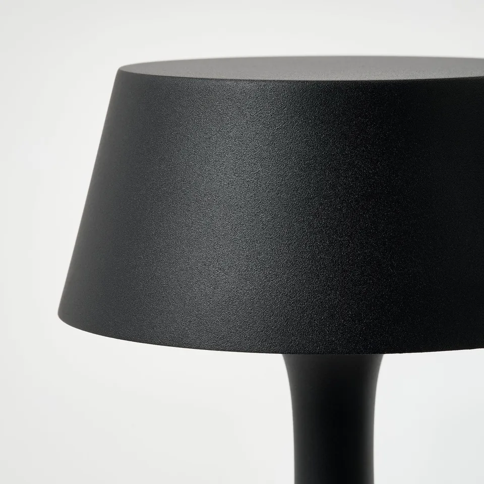 Black lamp shade on a round base, sleek and modern design.