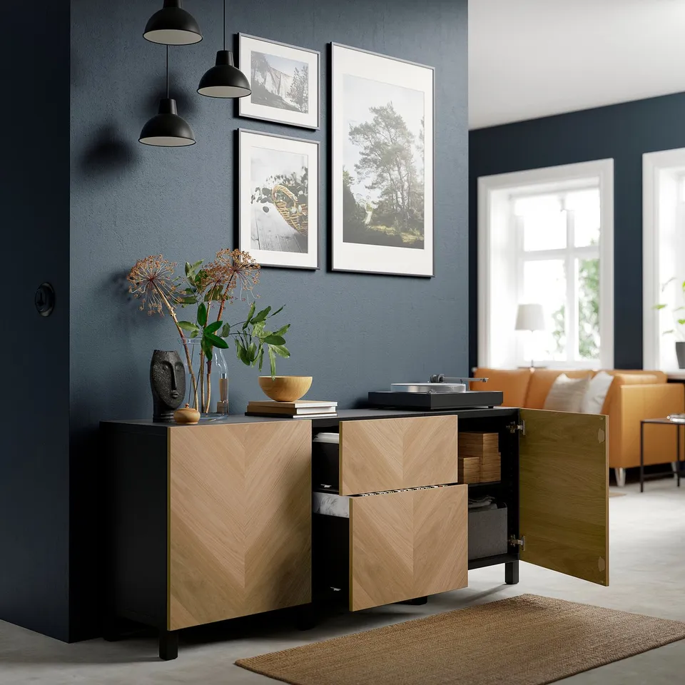 Modern room with dark blue walls. Wooden cabinet, vase, and pictures. Sunlit window.