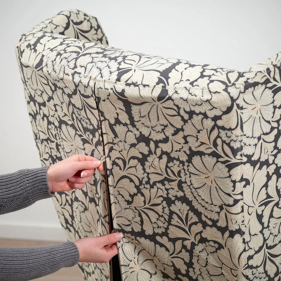 Person adjusting zip on decorative chair cover.