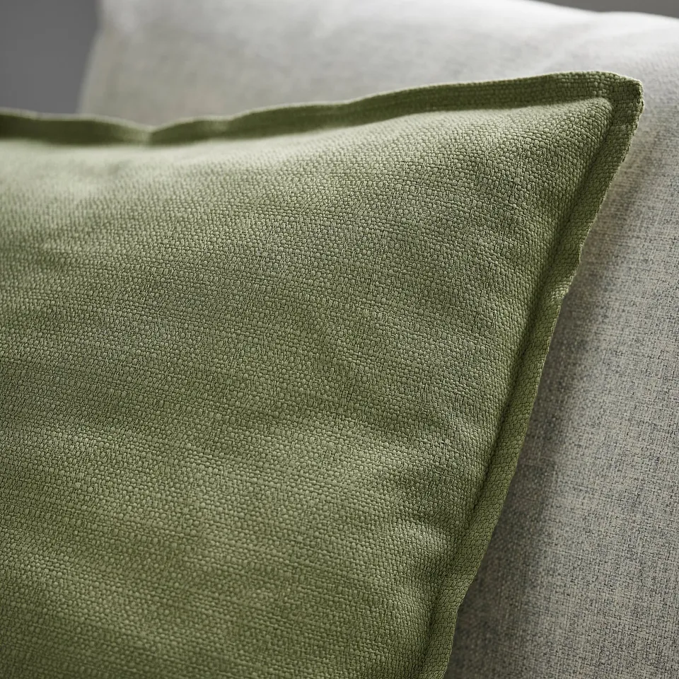 Green cushion cover with zip, textured, matte finish, detailed edge.