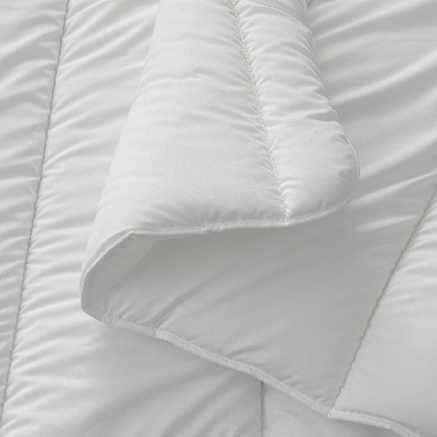 Soft, white comforter shown in close-up, highlighting plush, quilted stitching and fluffy texture.