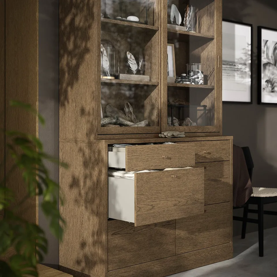 Modern wooden cabinet with glass doors, open drawer, displaying decorative items.