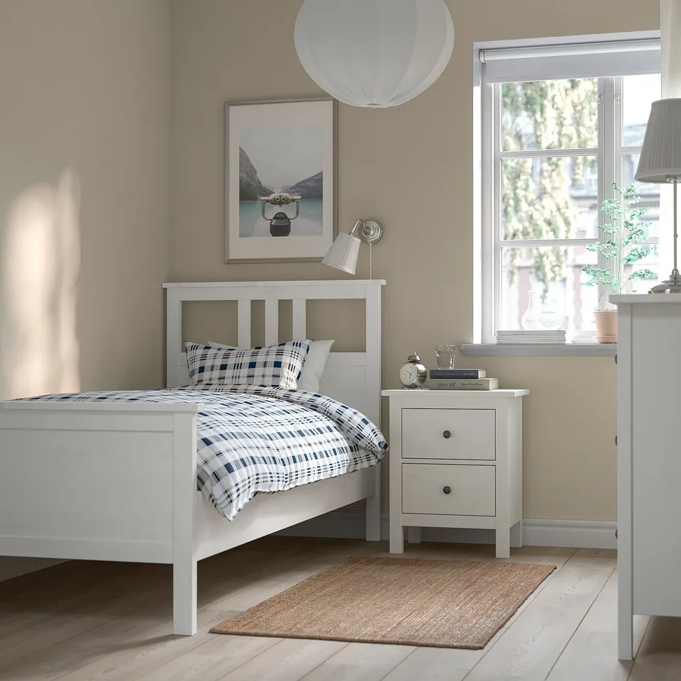 Bright bedroom: white HEMNES bed, drawer, rug. Art, lamp, plant, window.