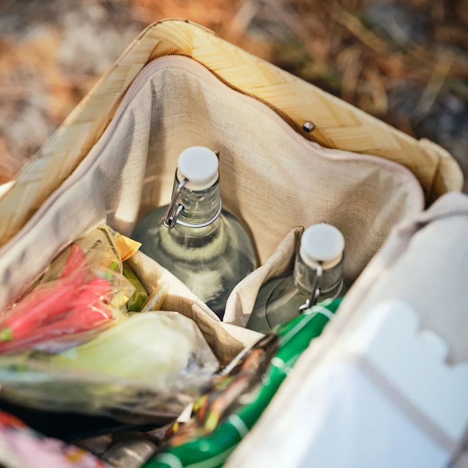 Cooling bag with bamboo shell holds drinks and food, keeping items separate and secure.