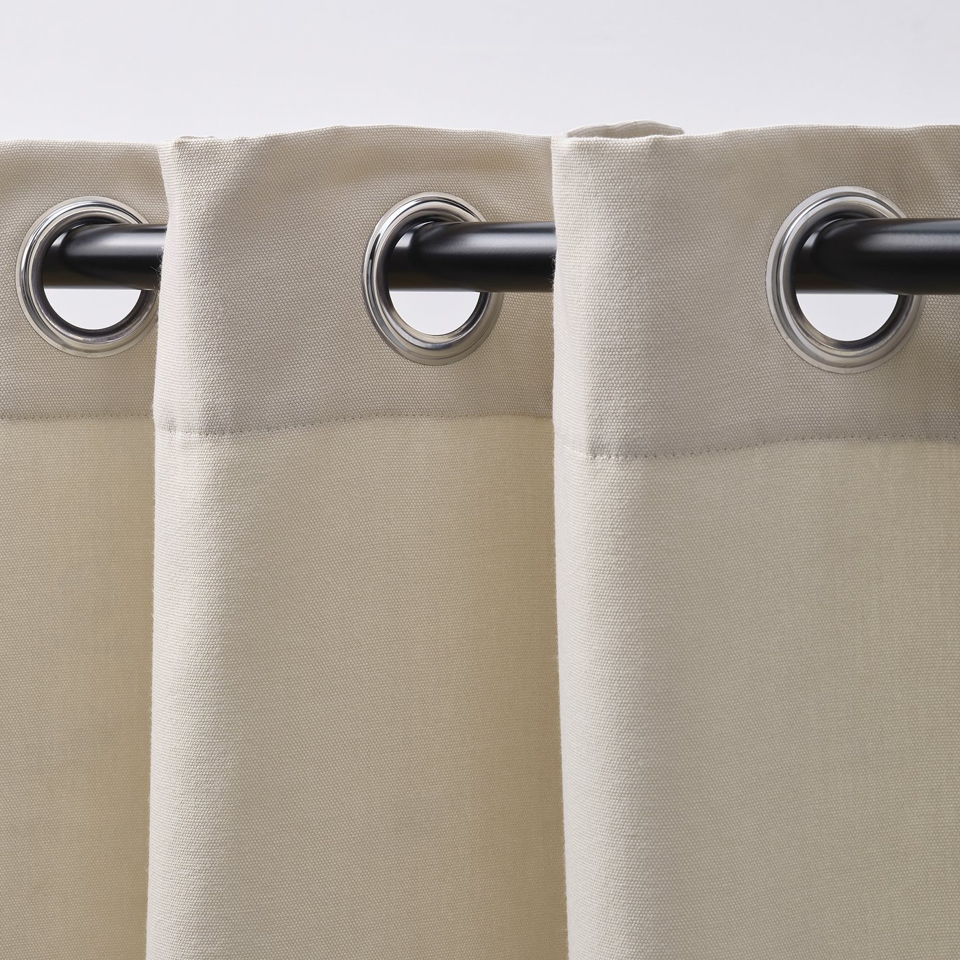 Beige curtains with eyelets for easy sliding, offering privacy while dimming daylight.