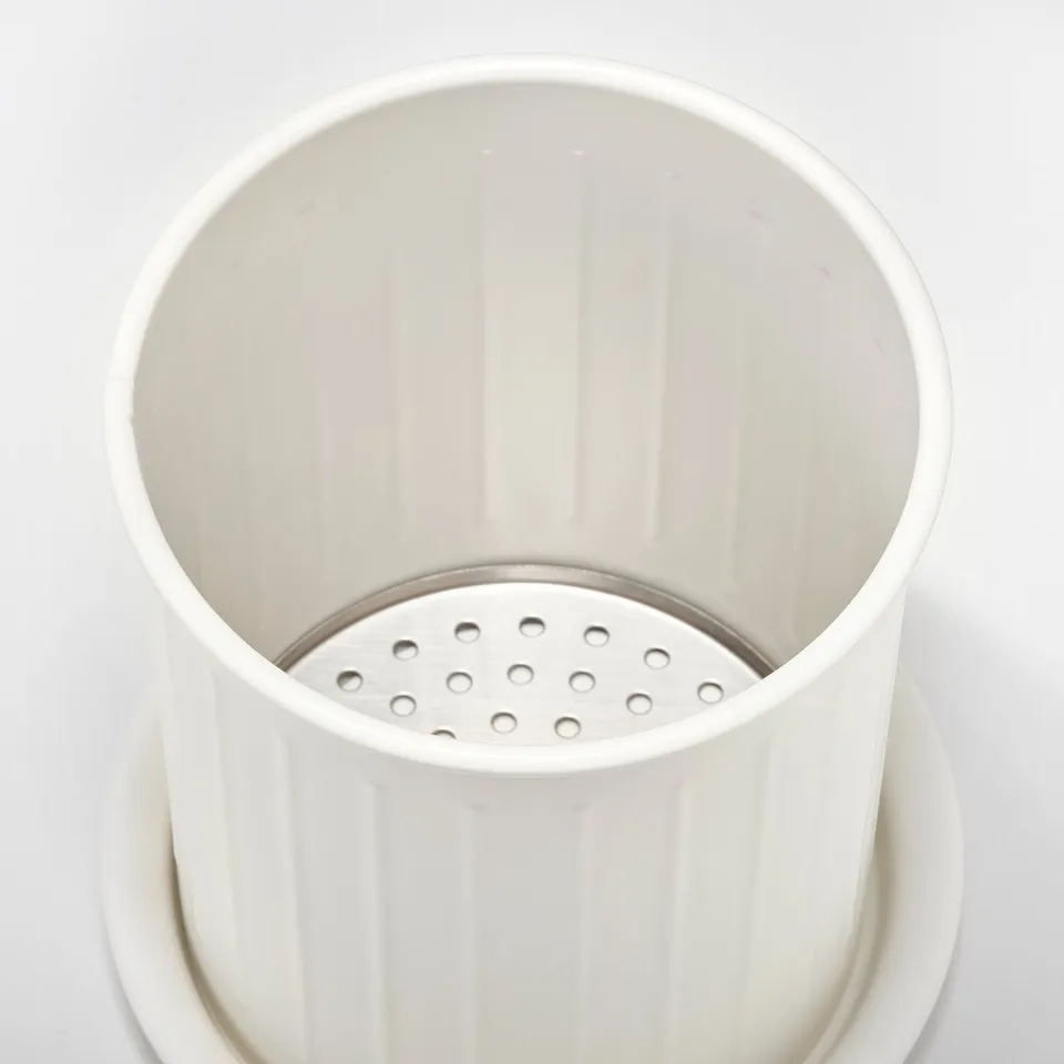A sleek, white, cylindrical kitchen utensil holder with vertical ridges and a perforated stainless steel base for draining.