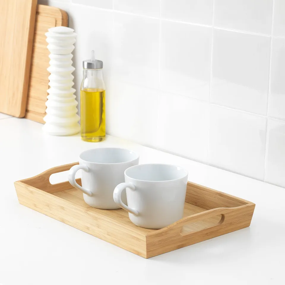 Wooden tray holding two white mugs on kitchen counter.