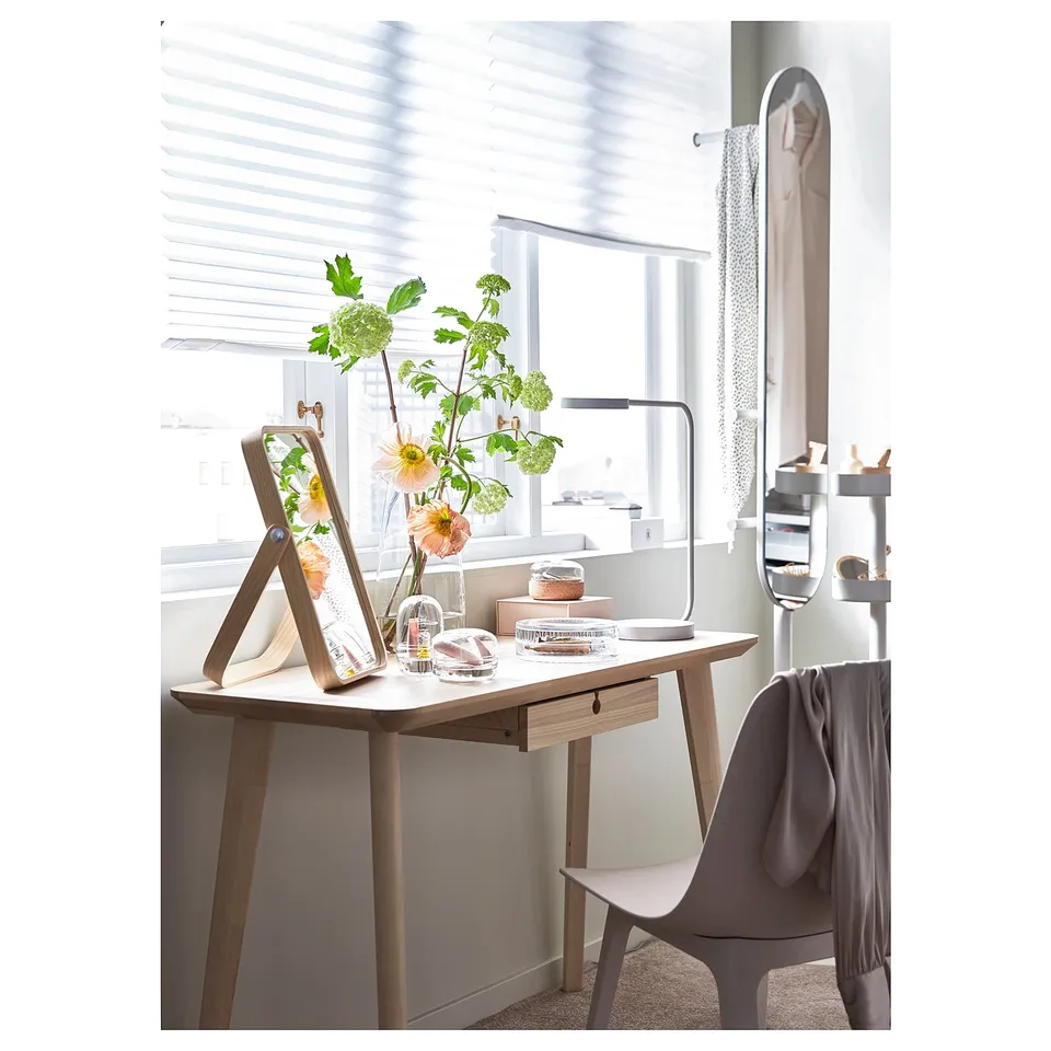 A sleek, light-filled workspace with an ash-veneered desk, grey chair, and an oval mirror, which can be wall-mounted or used as a scarf hanger.