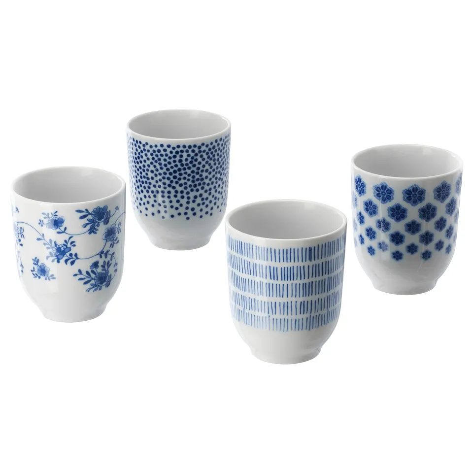Four blue and white ceramic cups with floral and dotted designs, arranged in a line.