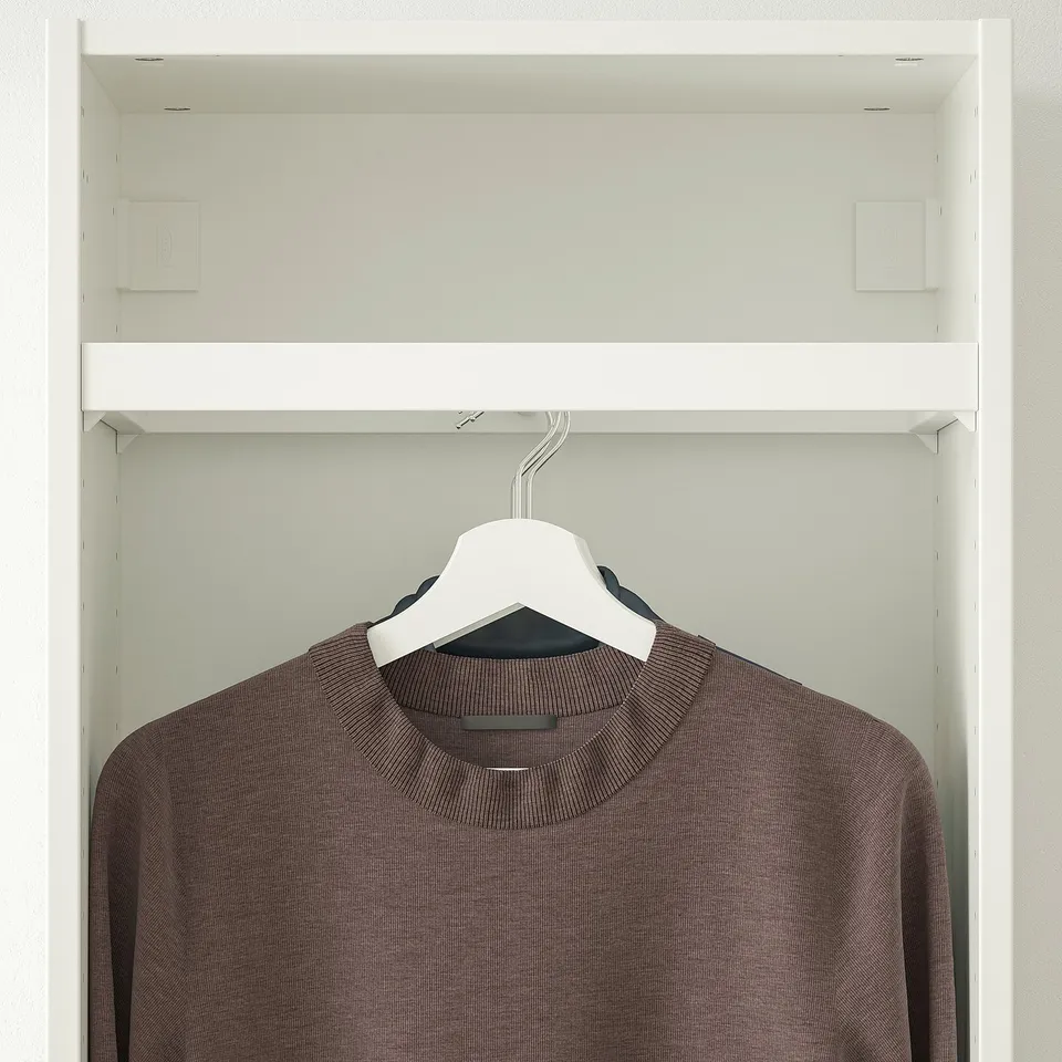 Image shows KOMPLEMENT clothes rail in a wardrobe, holding hangers with a sweater, demonstrating its hanging capacity in a shallow frame.