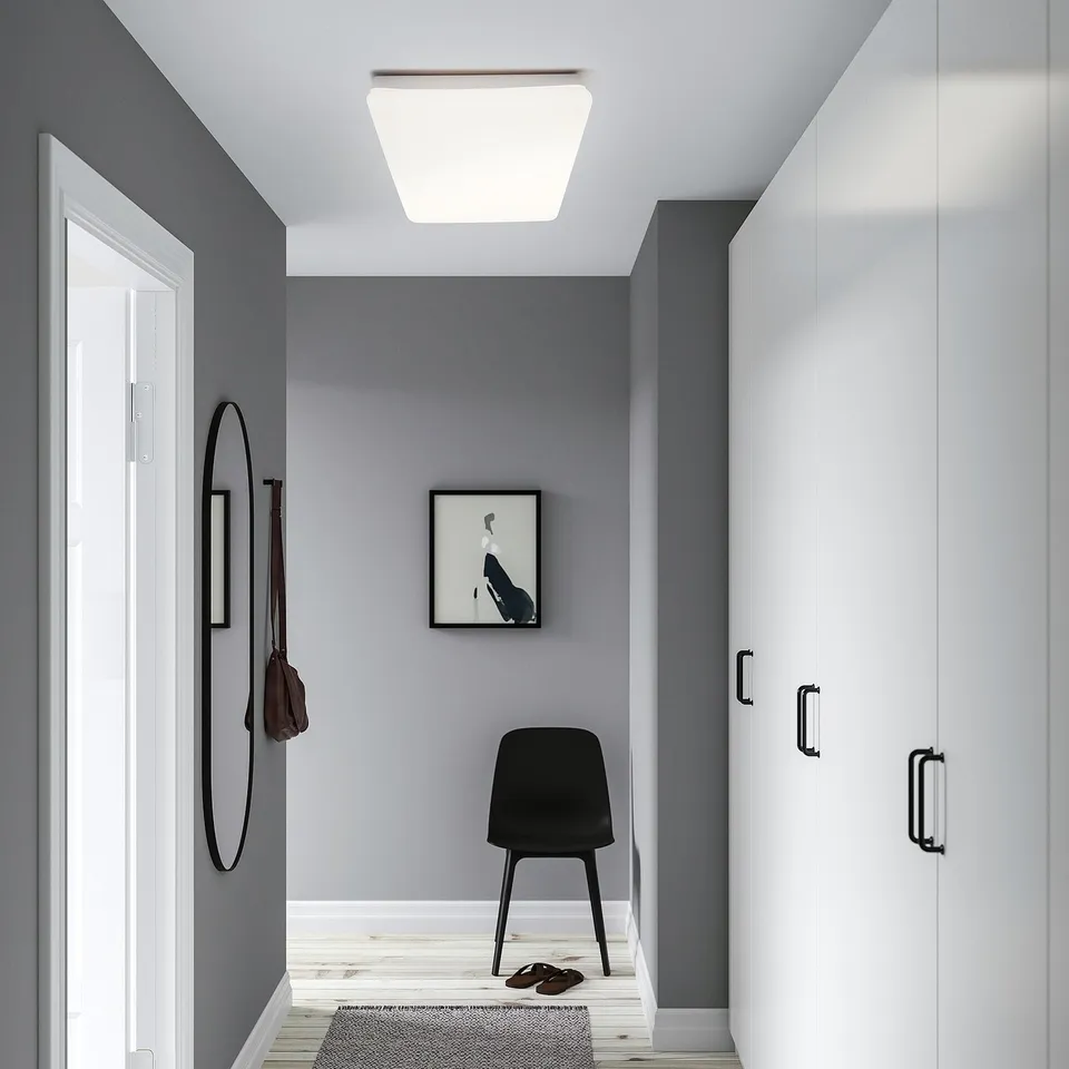 Modern hallway with ceiling light, mirror, bag, chair, art, cabinet.
