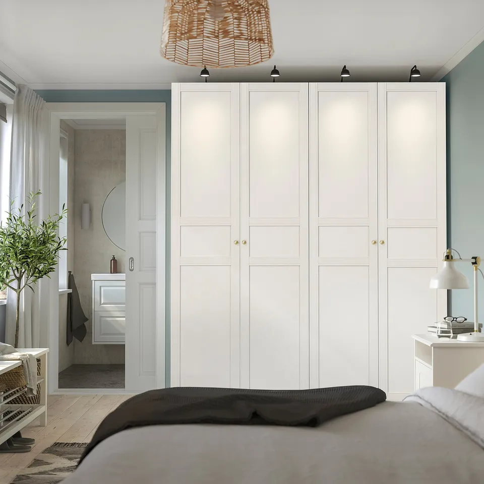 Minimalist bedroom with large off-white wardrobe, pendant light, and bedside lamp.