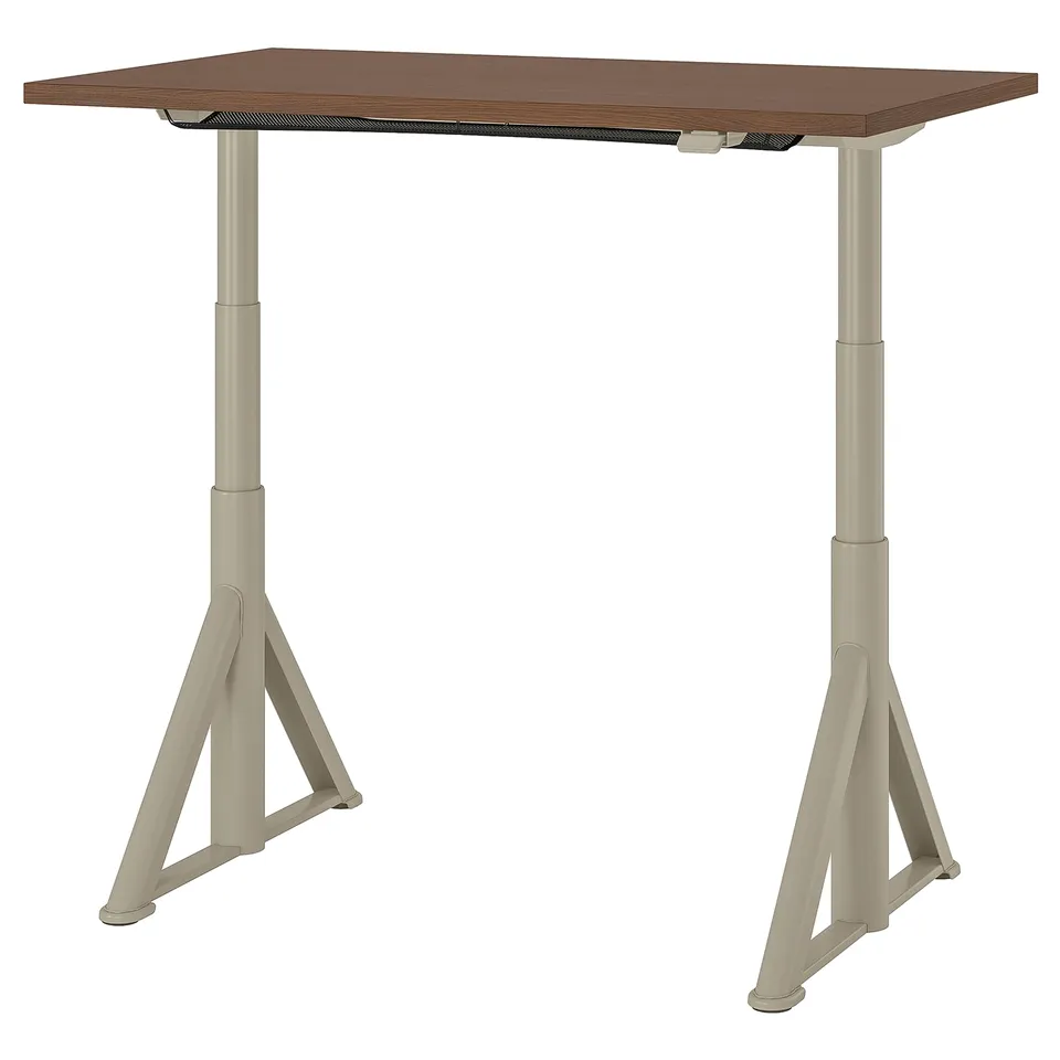 An IKEA idaosen desk in brown. It has an adjustable height, supported by beige metal legs with triangular bases.