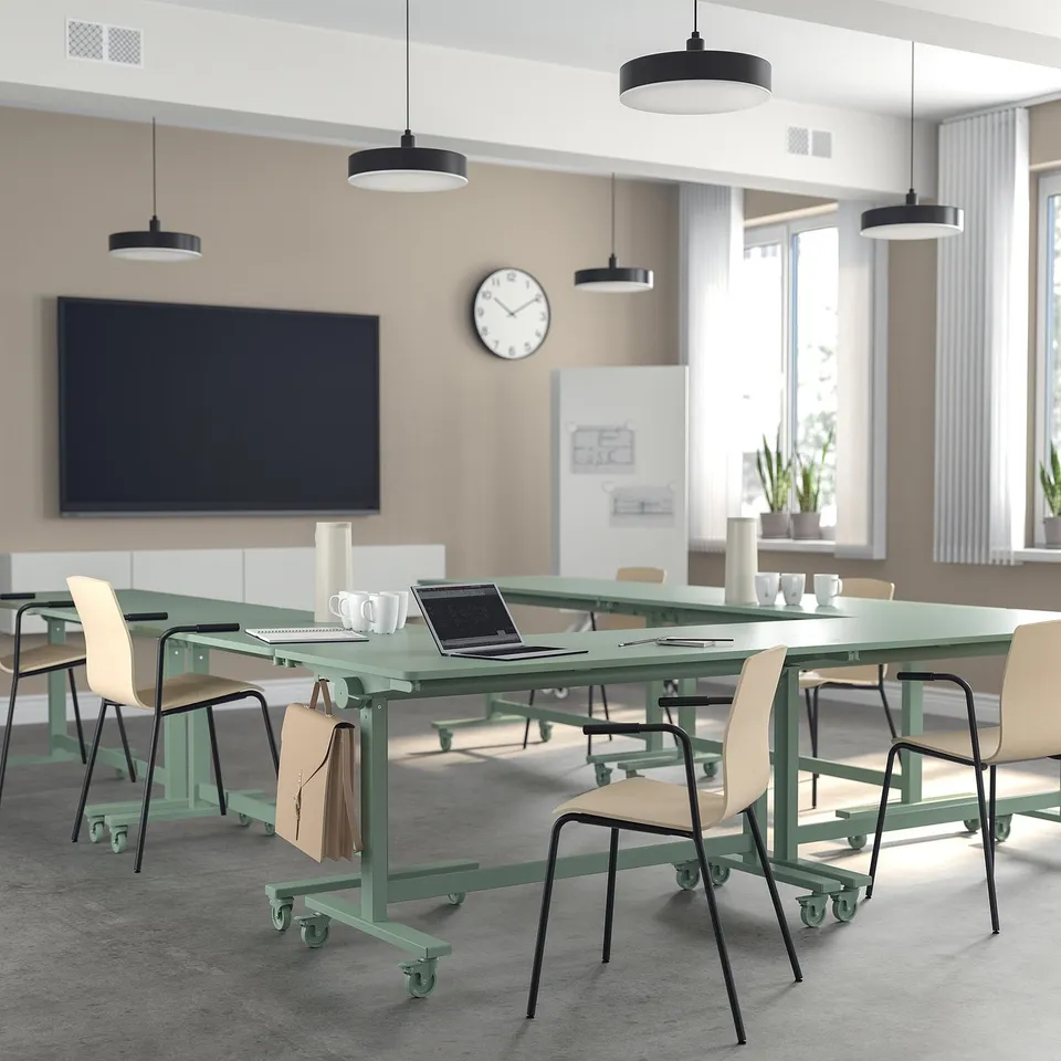 Office with MITTZON tables, chairs, lights, plants, clock, and screen. Green, rectangular, foldable tables on wheels.