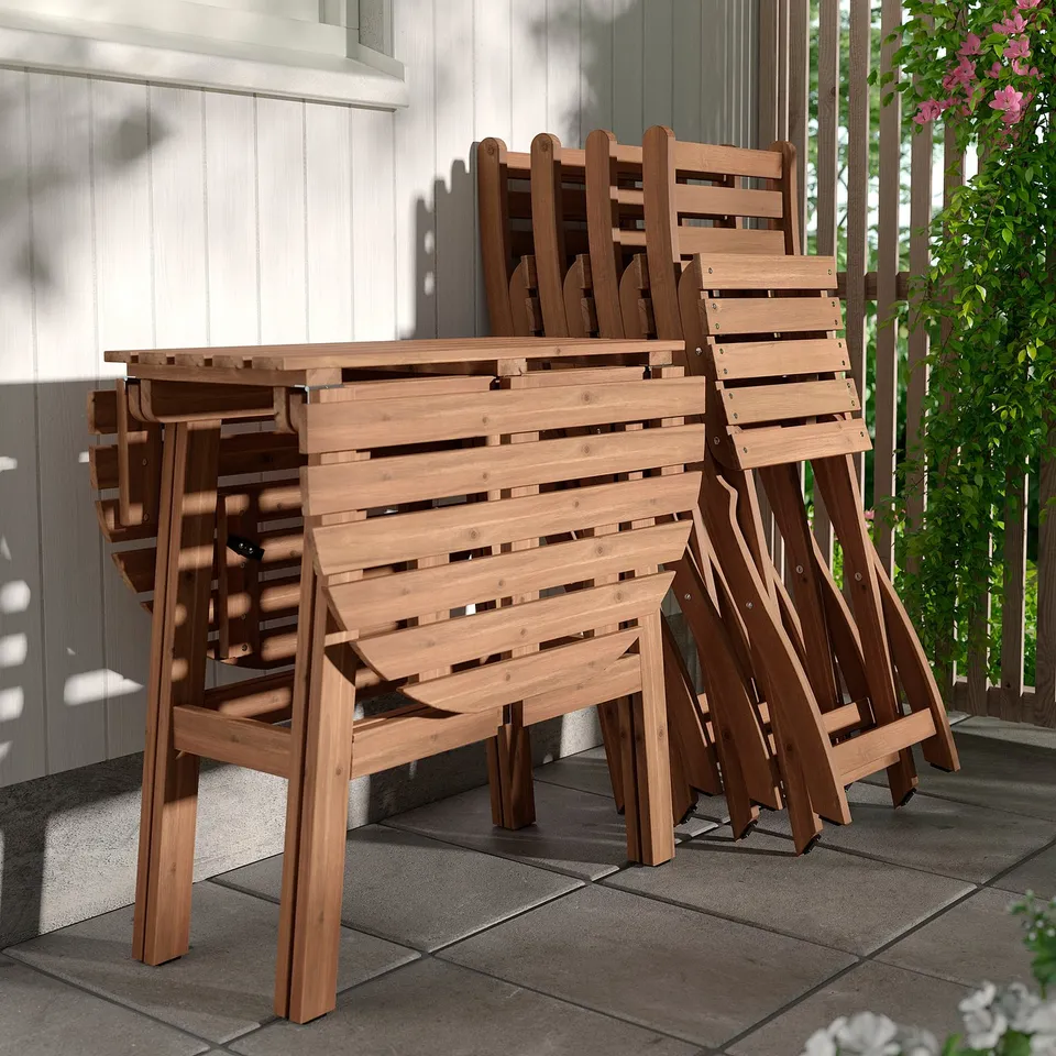 Stacked wooden patio furniture, including a table and chairs, designed for outdoor use.