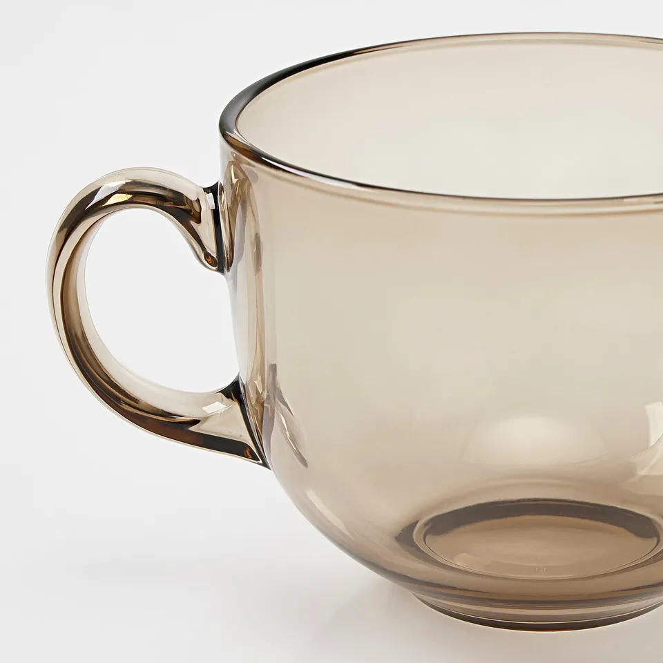 A large, sturdy glass mug with a comfortable handle, part of the HÖSTAGILLE collection, made of tempered glass for durability.