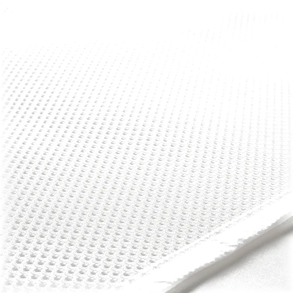 Close-up of a textured white mattress protector, showing its ventilated mesh surface with evenly distributed small holes.