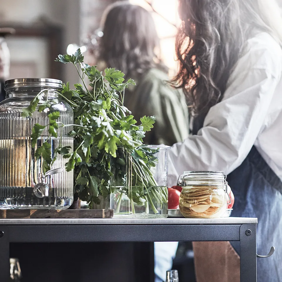 Cooking with fresh herbs in modern, sunlit kitchen.