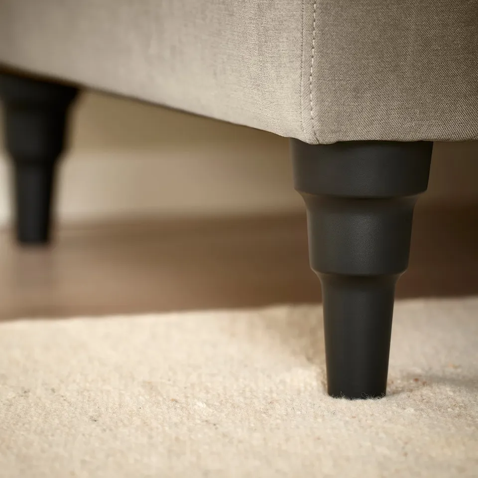 Close-up of a modern sofa leg showcasing robust, black plastic construction, highlighting quality and stability.
