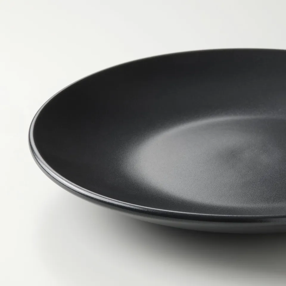 Black stoneware plate with a smooth, glossy finish. Simple, rounded design, shown from a slight angle.